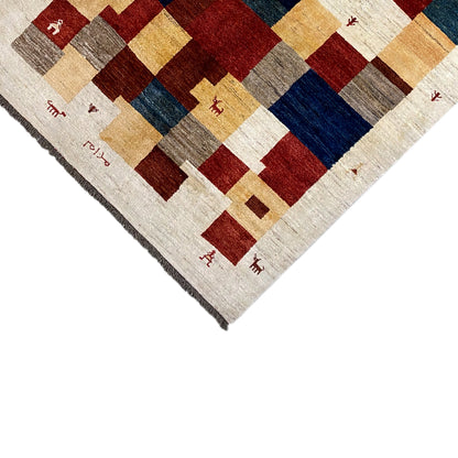 Gabbeh rug corner with fringed edges, square pattern in cream, red and dark blue