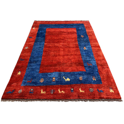 Gabbeh rug laid flat: red background with blue inner border and animal motifs