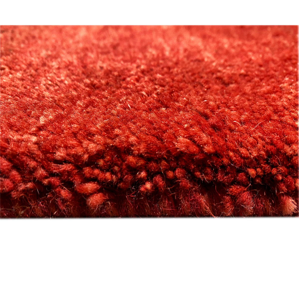 Close-up of a Gabbeh rug’s pile: dense red fibers with a short, fluffy texture