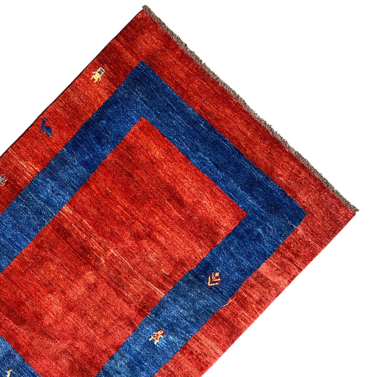 Corner of a Gabbeh rug: red field, broad blue stripe, and small colorful symbols