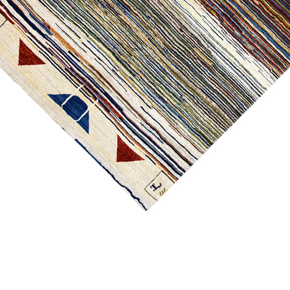 Corner of the Gabbeh rug: light border with triangular and block ornaments, multicolored stripes