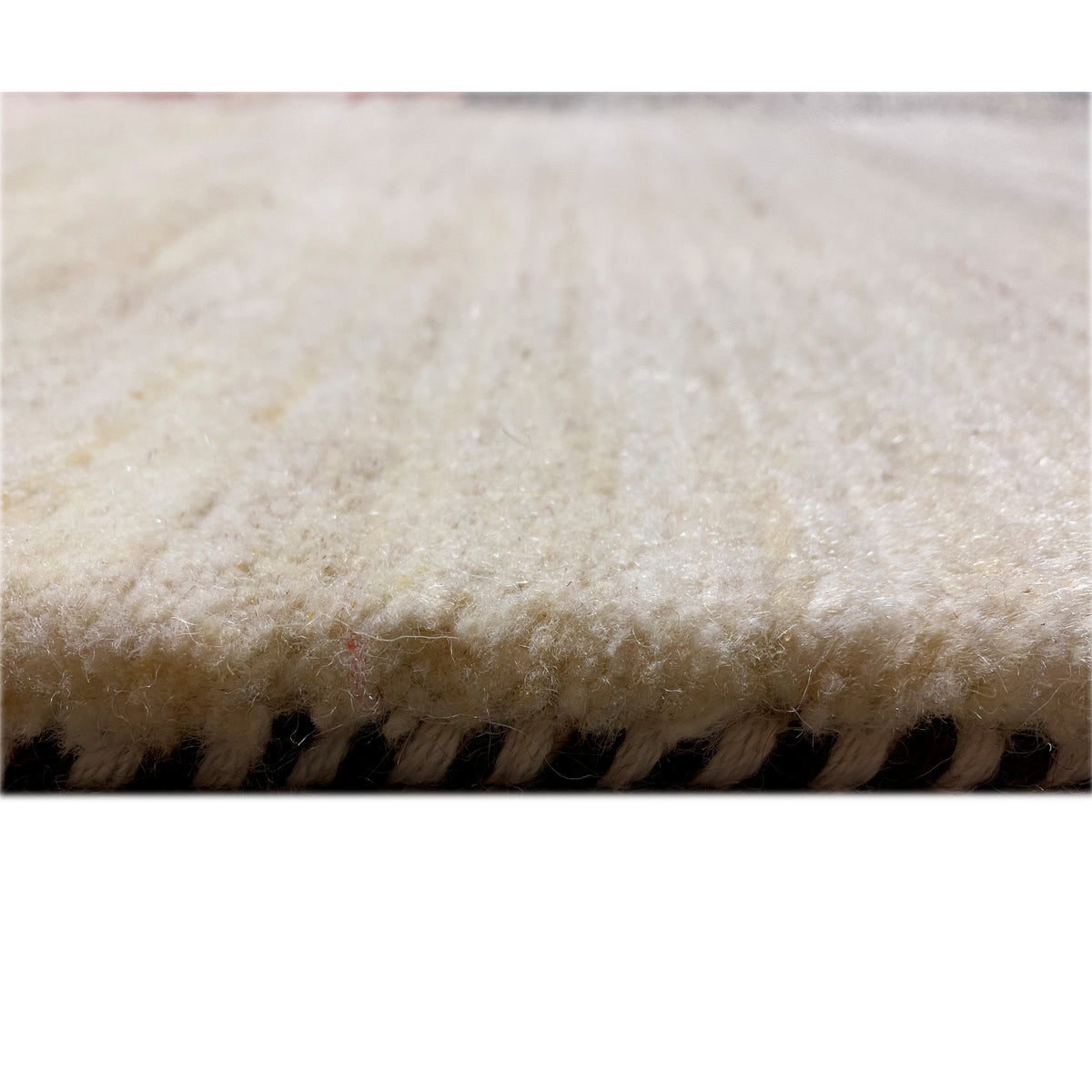 Gabbeh rug close-up: light fibers with a dark border along the edge