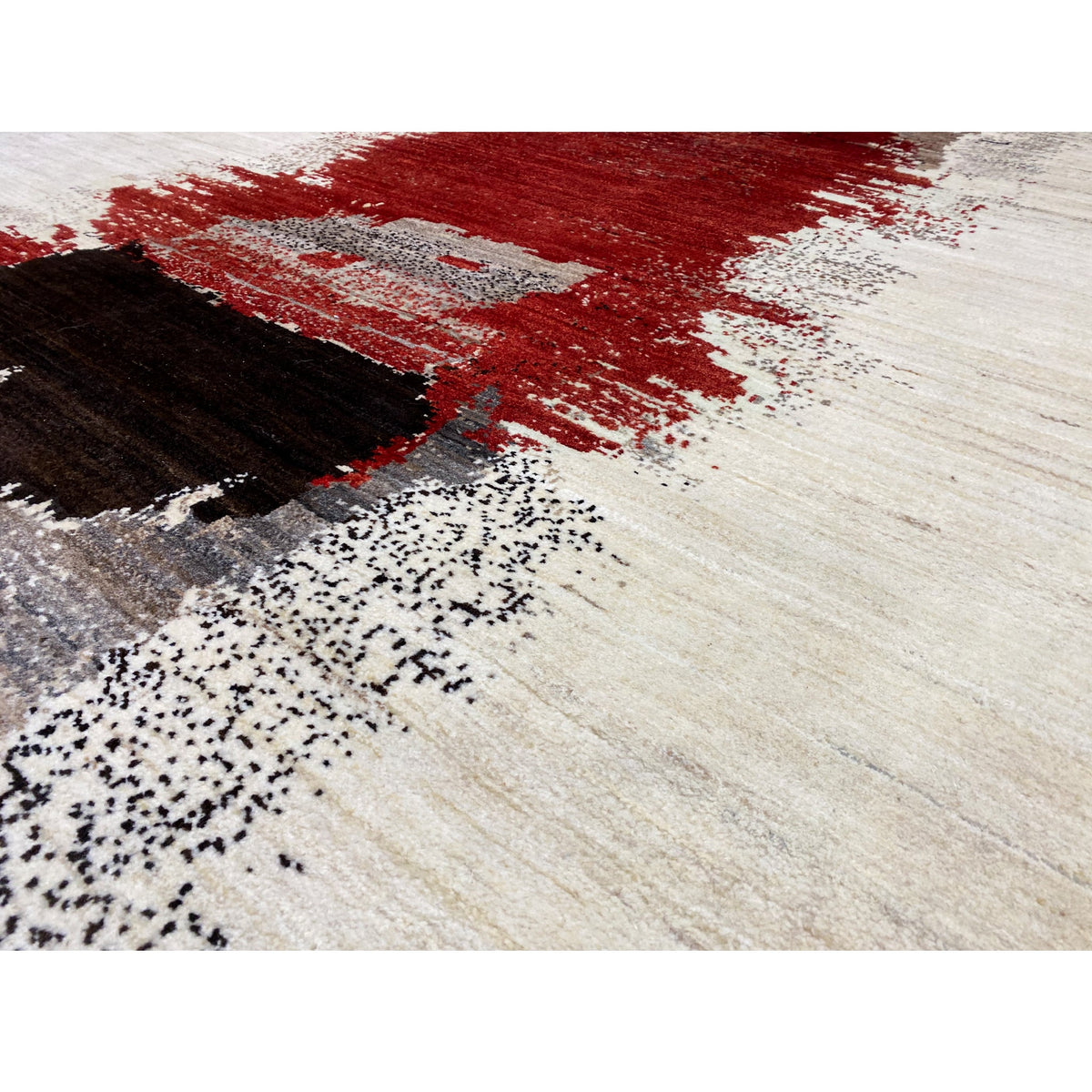 Close-up of a Gabbeh rug: red stripe, black elements, and fine gray speckles on beige