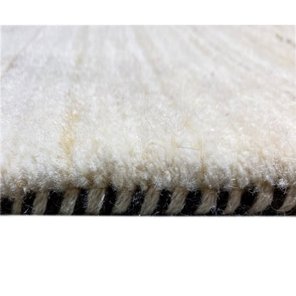 Gabbeh rug detail: dense beige pile with a jagged edge along the side