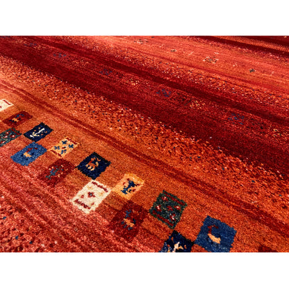 Close-up: red Gabbeh rug with blue-and-white patterned fields in a striped design