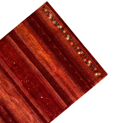 Red Gabbeh rug at an angle, wide stripes and small multicolored squares