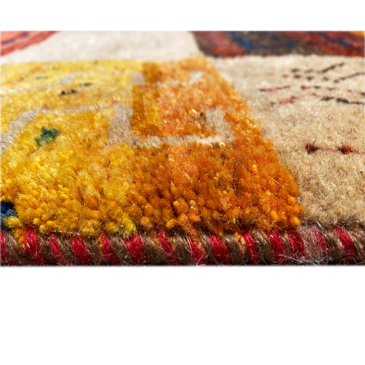 Close-up of the web structure at the edge: soft pile fibers in yellow, brown, and beige, with fringes visible