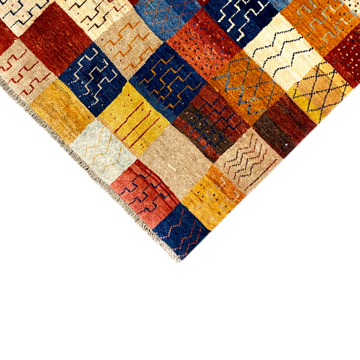 Gabbeh rug corner in detail: fringes, patchwork ornaments in red, blue, yellow and cream