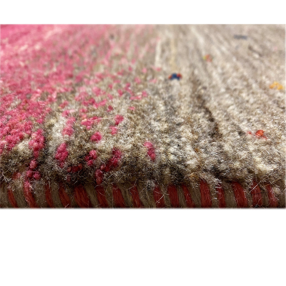 Close-up of a carpet surface with pink elements and gray pile, edge area visible