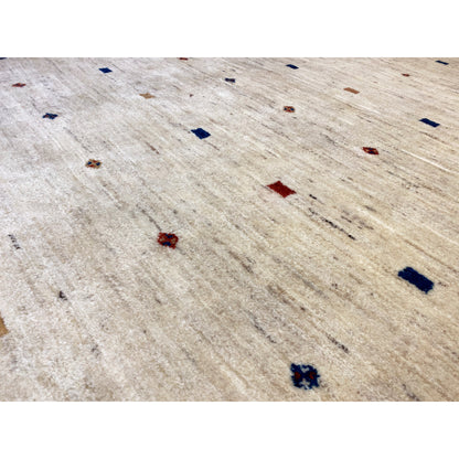 Close-up of a Gabbeh rug: light beige pile with red and blue patterned dots