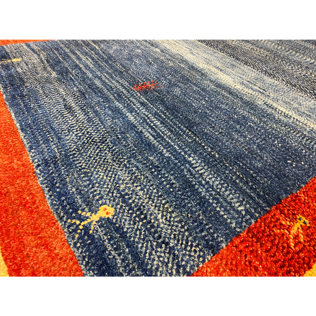 Close-up of carpet pile: blue-gray texture, red border, and fine patterned dots