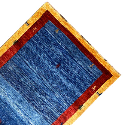 Corner of the carpet with a blue inner field, red border, and beige edging