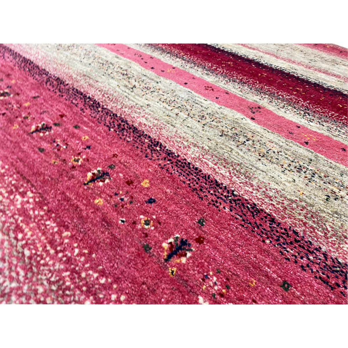 Close-up: Gabbeh rug with red and beige stripes, a mottled surface, and dots