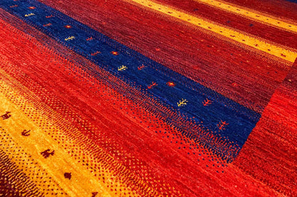 Gabbeh rug close-up: red background with blue areas and yellow dots