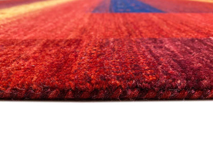 Gabbeh rug close-up: dense red pile with a visible edge