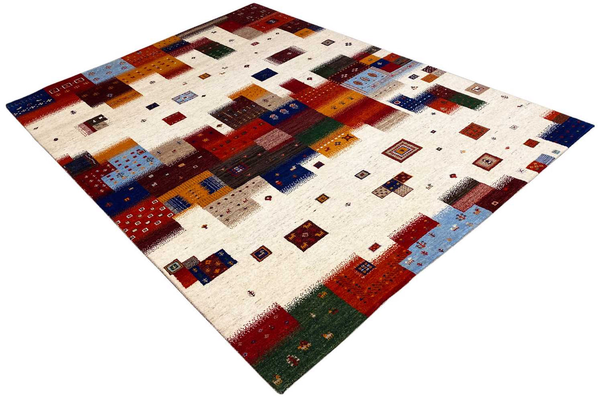 Gabbeh rug in angled view with patchwork patterns in shades of blue, red, and green on beige