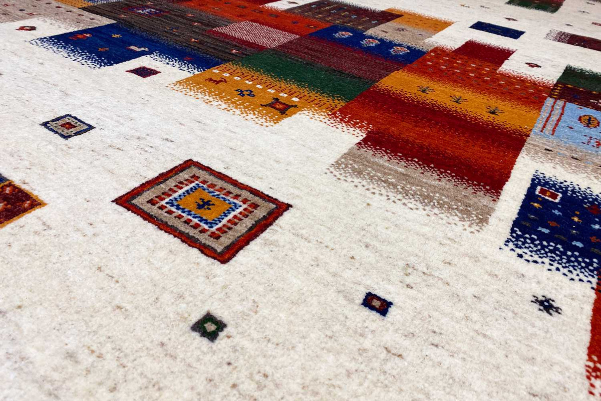 Gabbeh rug close-up with square ornaments in blue and red on a light background