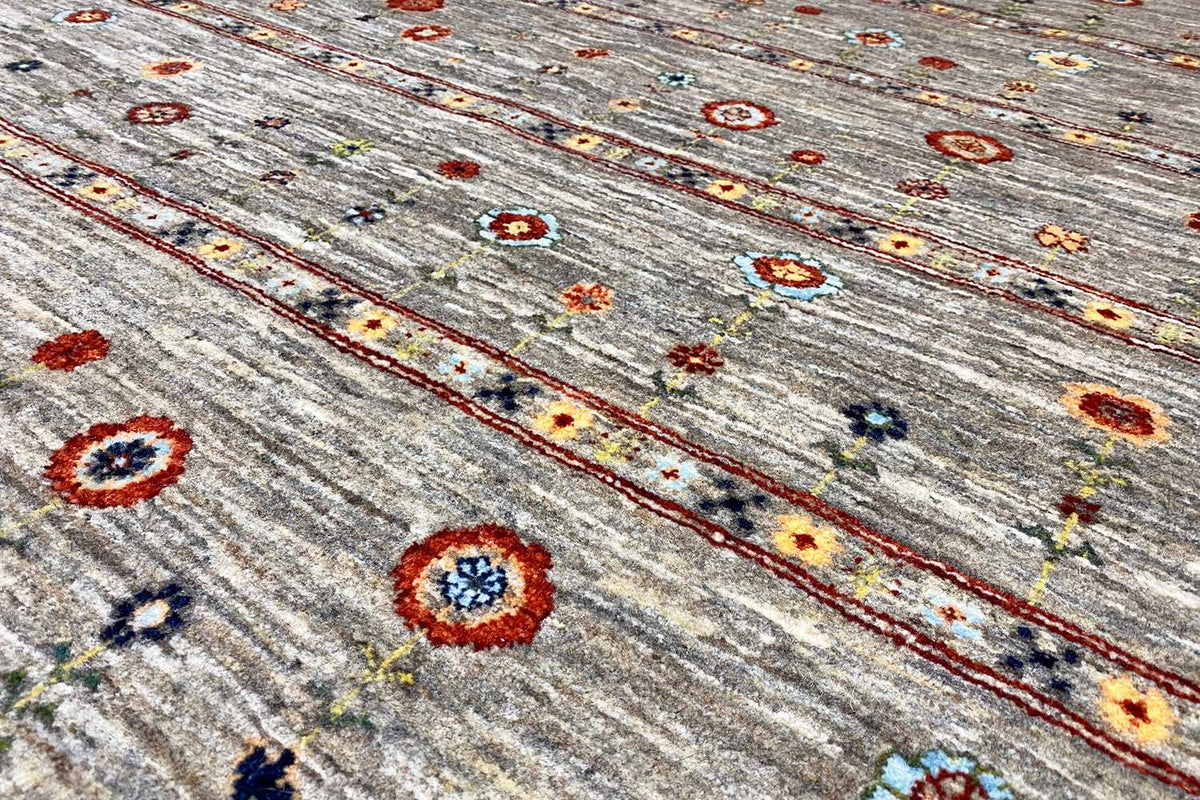 Gabbeh rug detail view: small circular ornaments and colorful flowers on a gray background