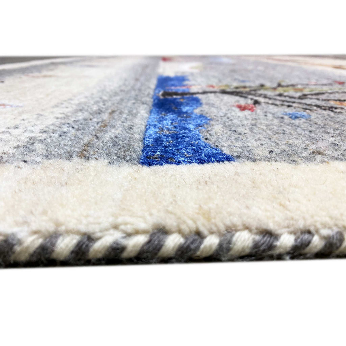 Gabbeh rug detail at the edge: short pile and braided fringe on a light background