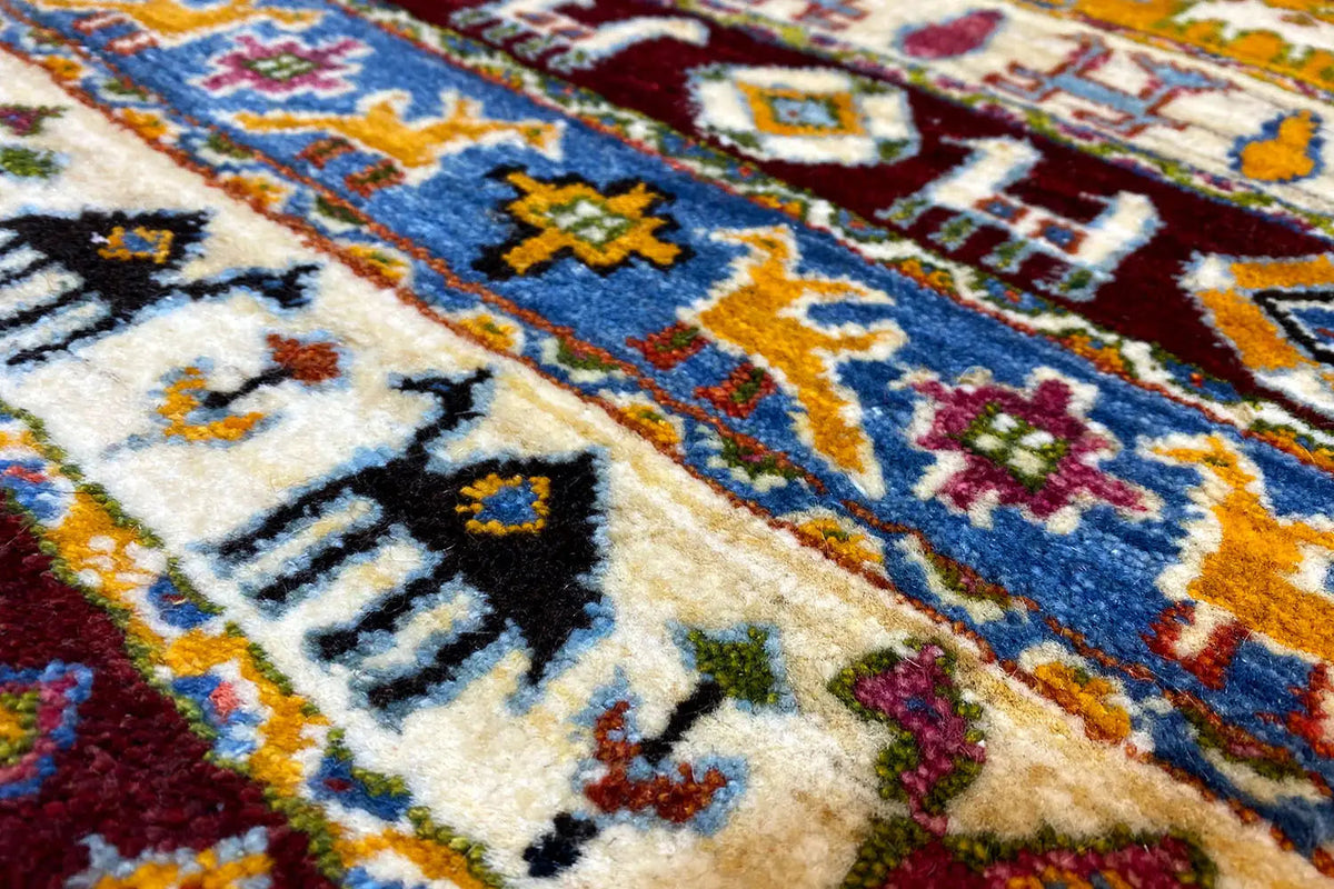 Gabbeh rug detail: cream-colored pile with blue, yellow, and red ornaments.