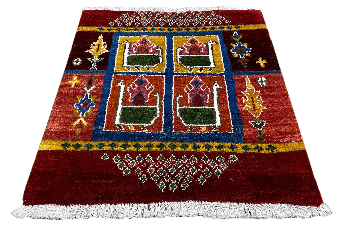 Red gabbeh rug with blue border, six house motifs in a grid, white fringes, 56x56 cm