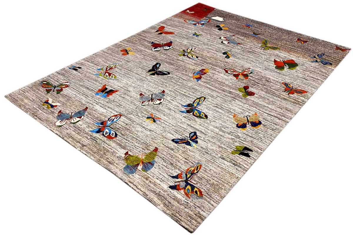 Gabbeh rug in diagonal view, light gray with colorful butterflies and a red corner panel