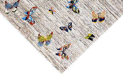 Gabbeh rug with colorful butterflies on a light, mottled background
