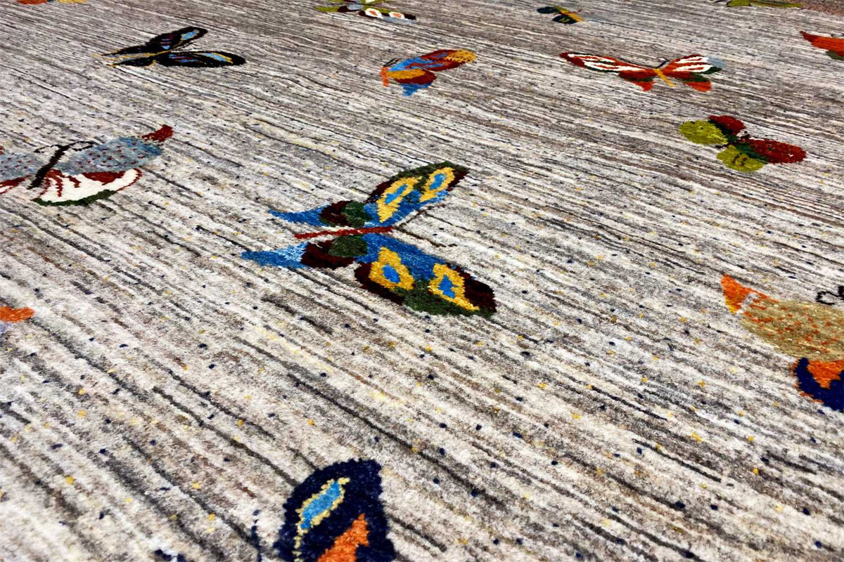 Close-up of Gabbeh rug: mottled light gray pile with colorful motifs