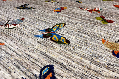 Close-up of Gabbeh rug: mottled light gray pile with colorful motifs