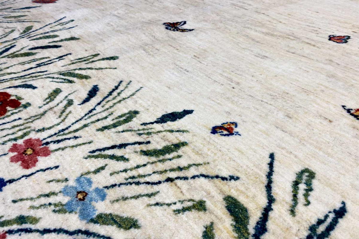 Gabbeh-Lori rug: detail with blue and red flowers, green grasses, and butterflies