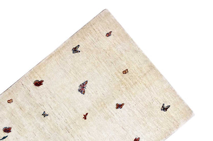 Gabbeh Lori rug: beige rug with scattered butterflies, rounded edge