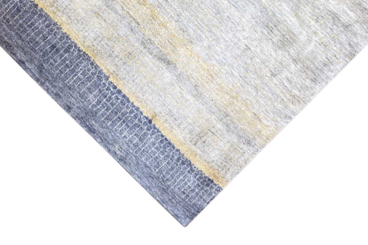 Corner of the Gabbeh-Lori rug: light gray area with a yellow stripe and blue border
