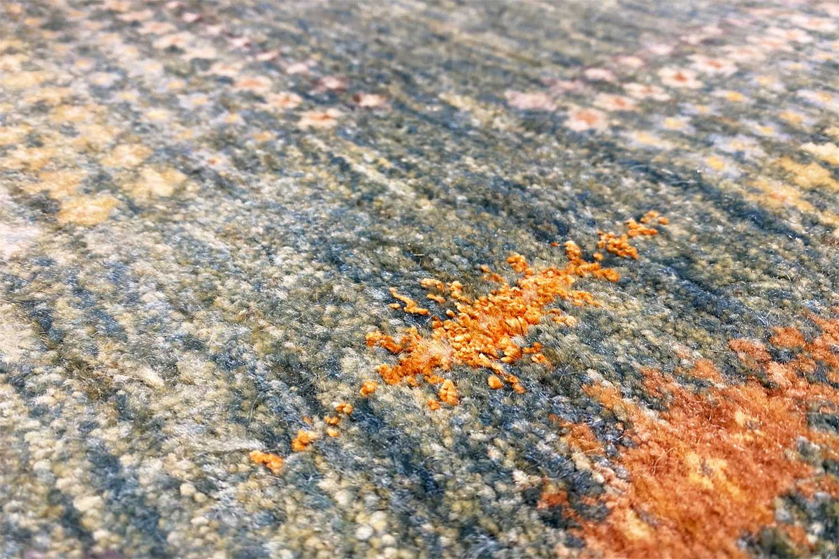 Detail view: Gabbeh Lori rug texture with orange flecks on a blue-gray background