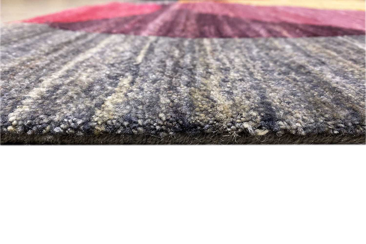 Gabbeh rug close-up of the pile surface and edge, dark gray with color accents