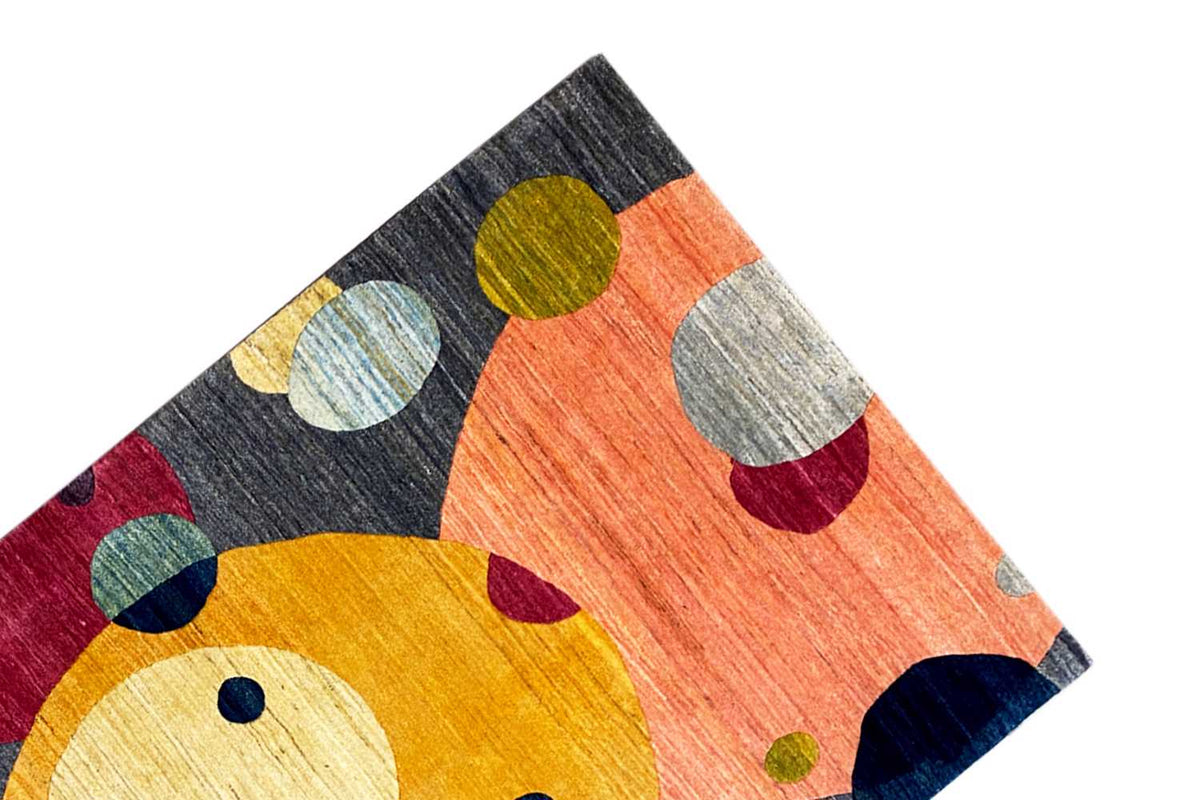 Gabbeh rug edge detail with orange and yellow circles on a dark gray background