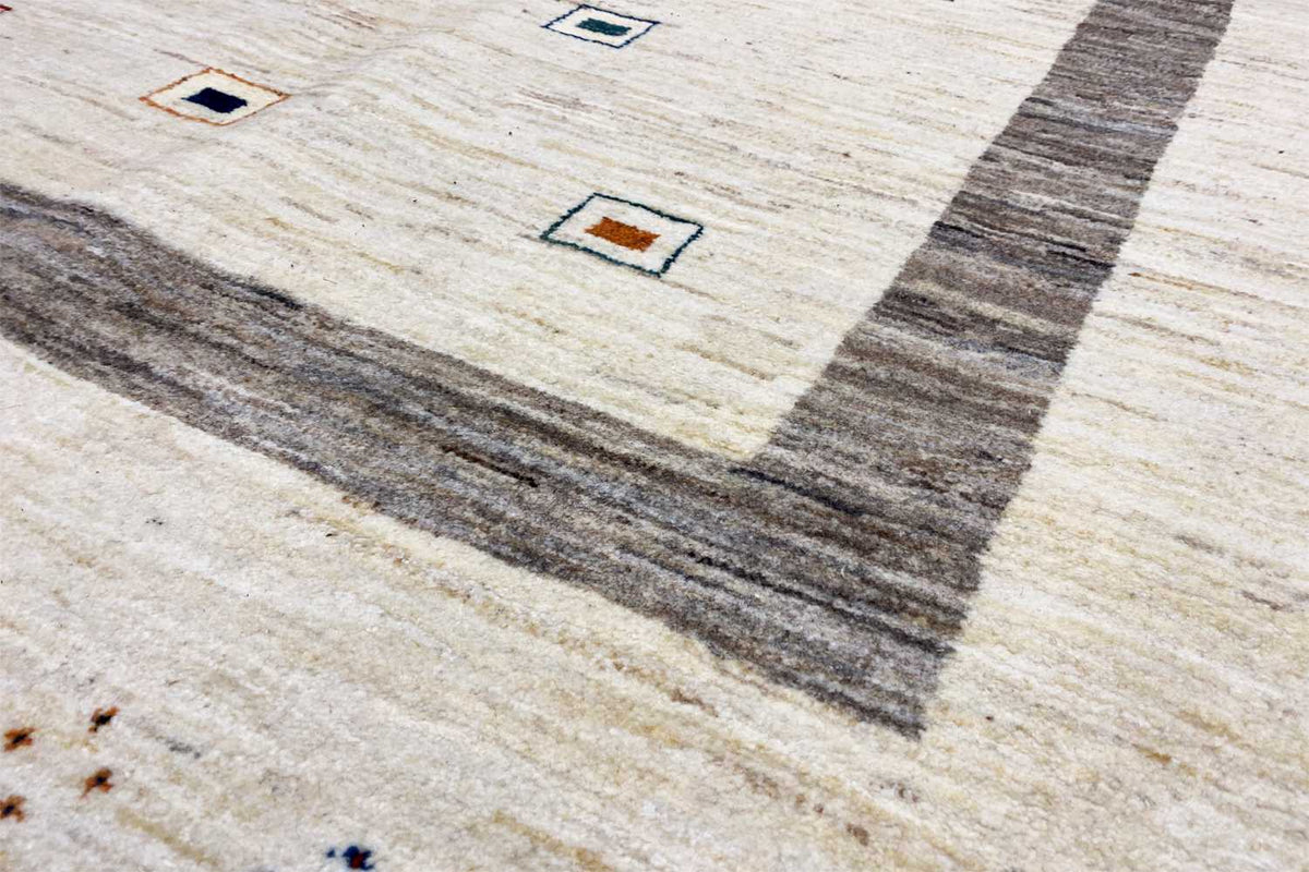 Detail view: beige Gabbeh rug with gray central stripes and small multicolored squares