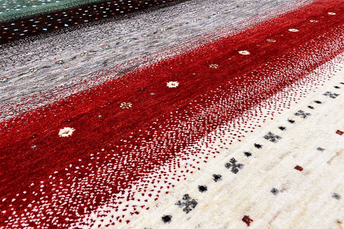 Close-up of a Gabbeh rug: red and gray surface with white dot patterns