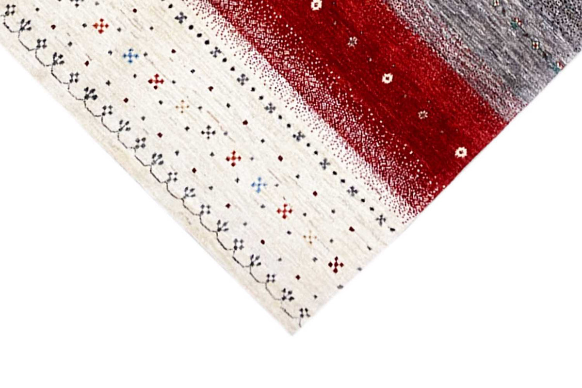 Corner of the Gabbeh rug: cream-colored patterned field with red and gray stripes