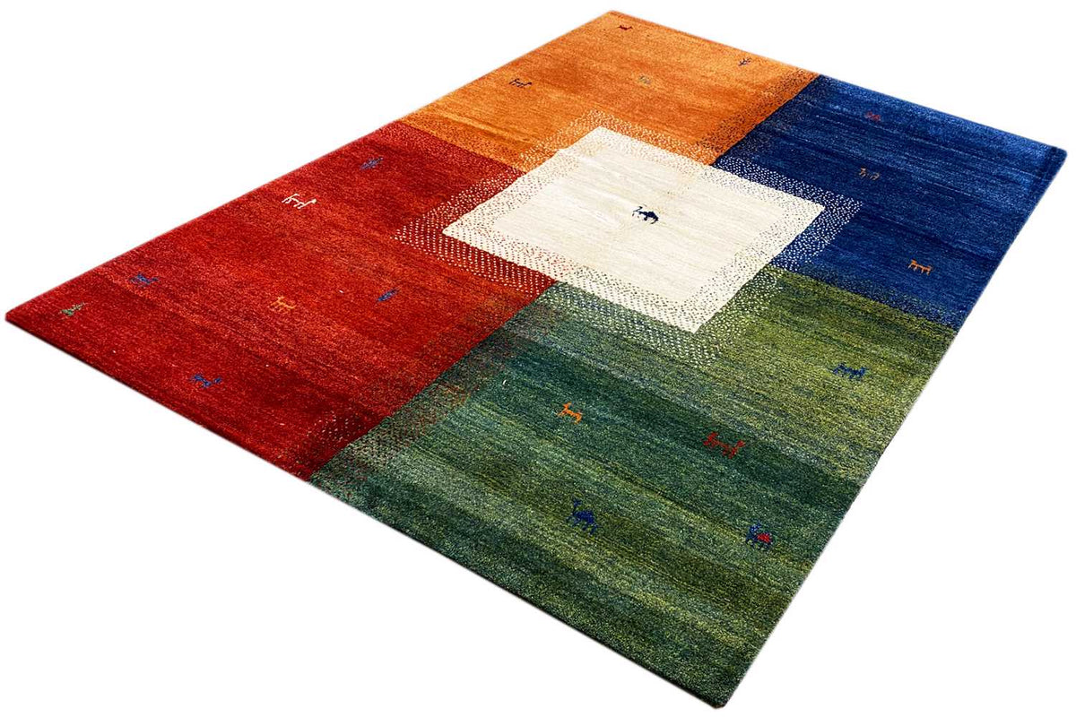 Multicolored Gabbeh rug viewed at an angle, with a white central motif and colorful borders