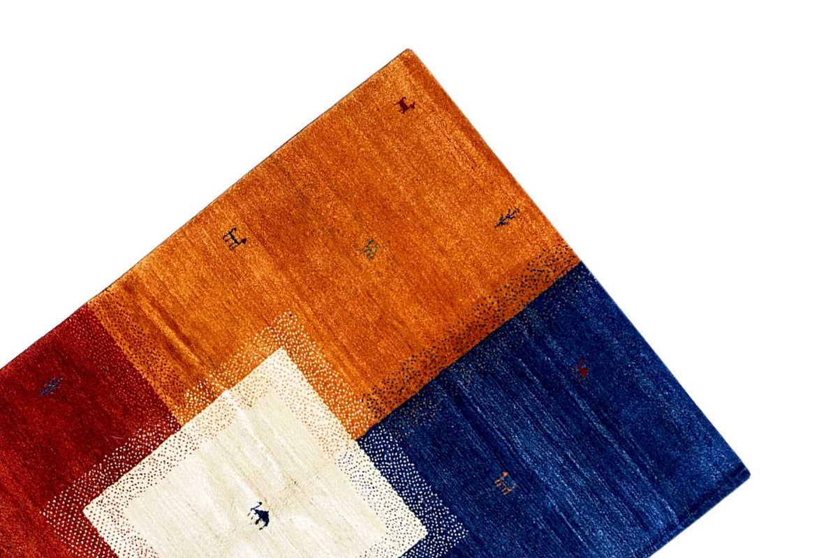 Multicolored Gabbeh rug corner in perspective with an orange-blue block pattern