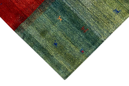 Multicolored Gabbeh rug corner: green field with small multicolored symbols