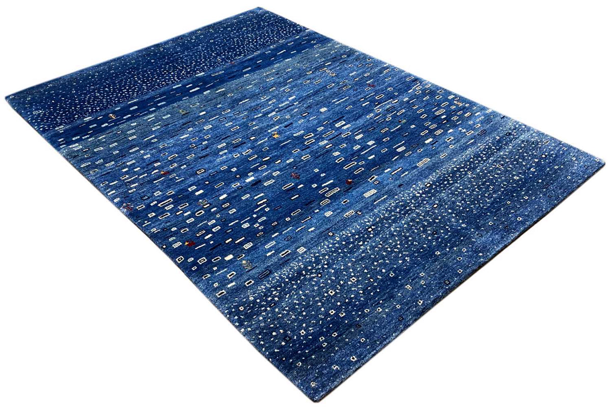 Blue Gabbeh rug, diagonal view with a fine patterned texture and striped border