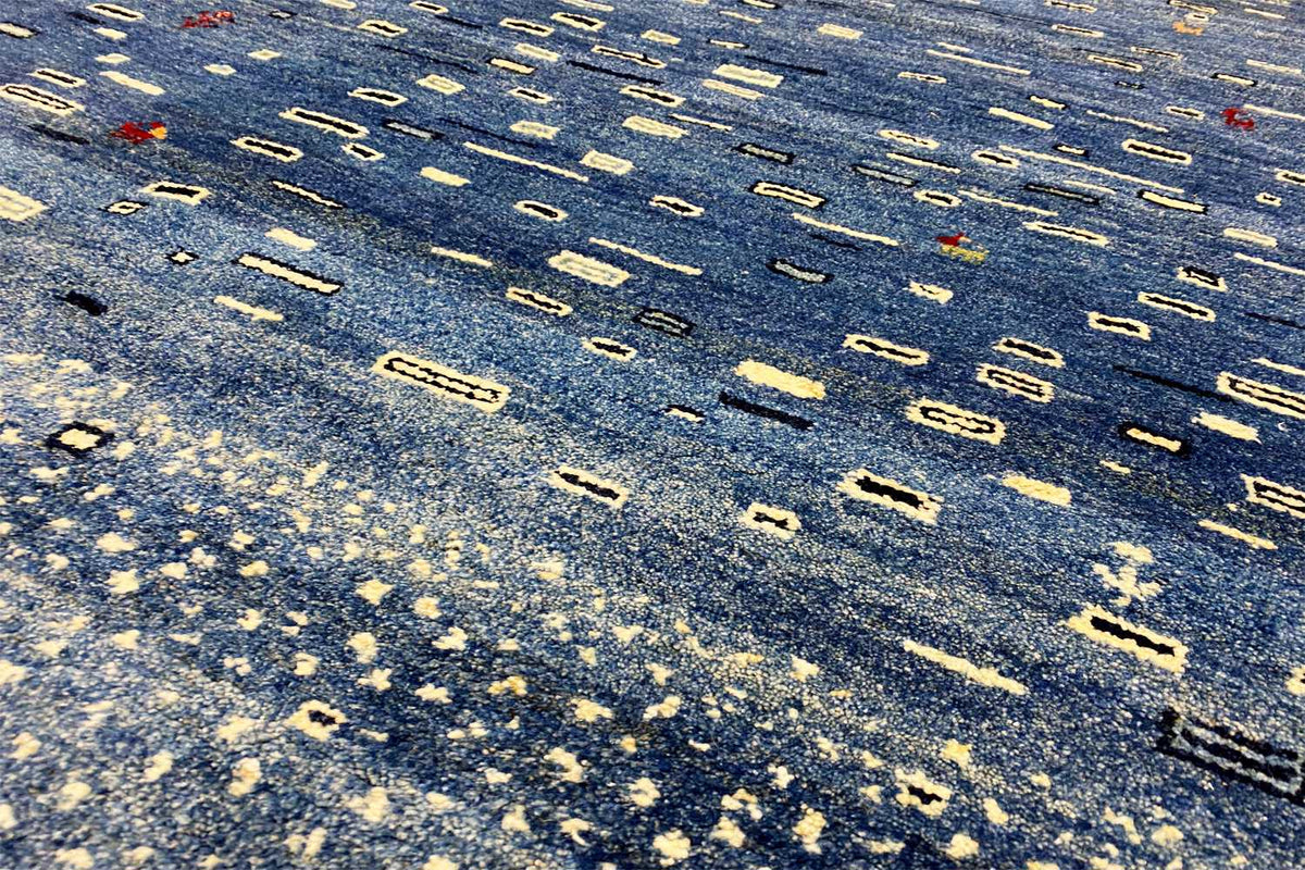 Close-up of the carpet surface: blue base fabric with light, elongated patterned shapes