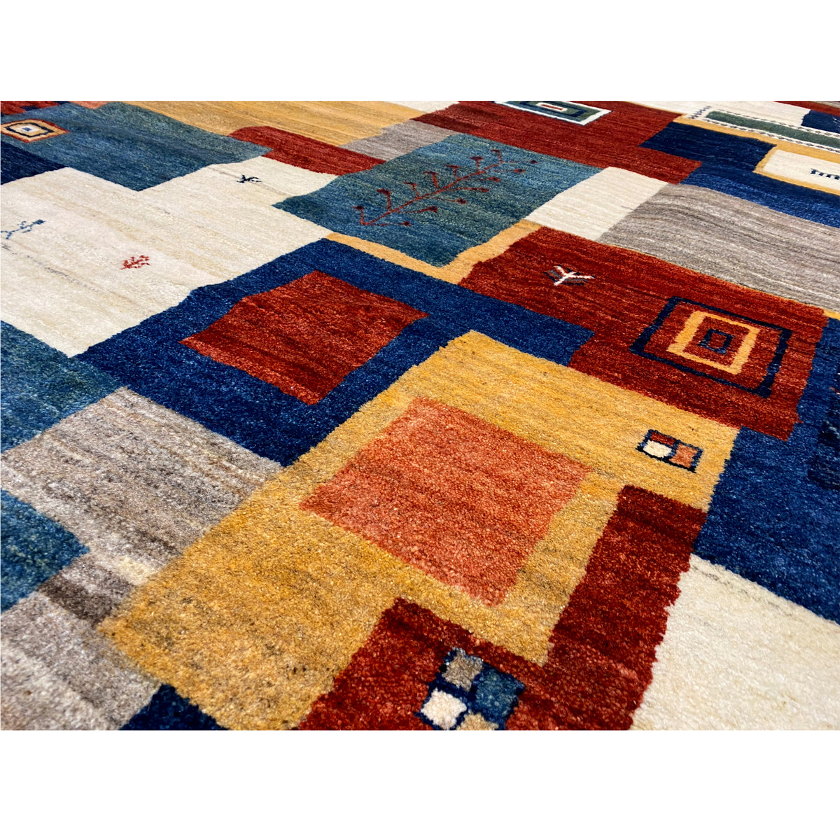 Gabbeh rug detail: patchwork tiles in blue, red, yellow, and beige