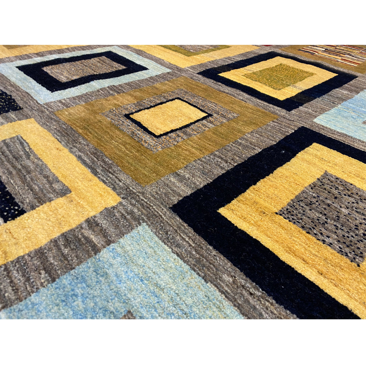 Detailed view of Gabbeh rug: woven squares in yellow, blue, gray, and black