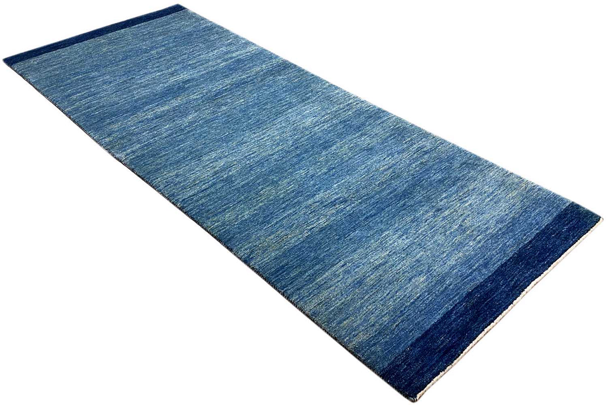 Blue runner rug 100x250 cm, laid out diagonally, mottled with a dark border.