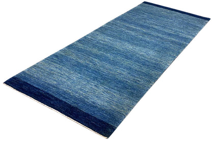Blue runner rug 100x250 cm, laid diagonally, with a uniform mottled look.