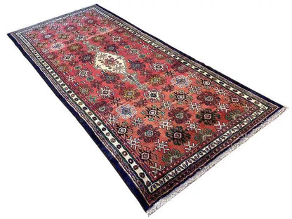 Oriental rug laid out: red pattern with medallion, blue border, and light decorative stripes