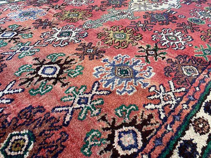 Close-up of carpet pile: red ornament with turquoise, green, blue, and yellow accents