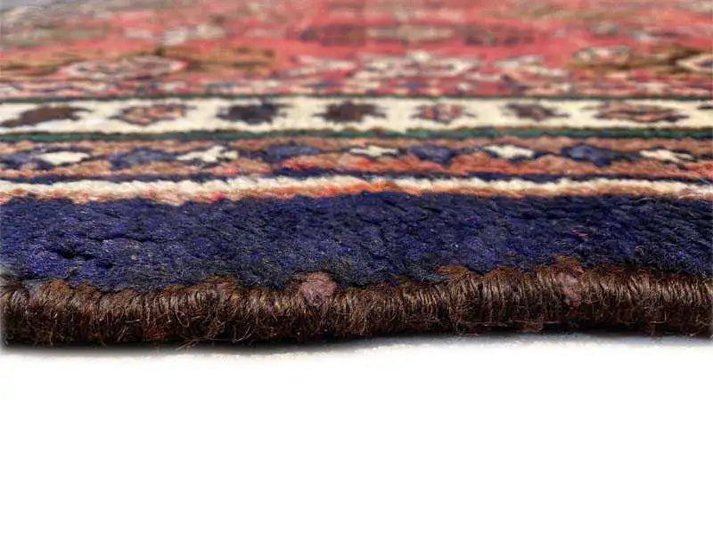 Carpet edge with a blue border and dark fringe trim, visible fabric thickness